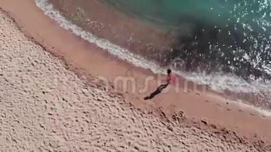 桑迪海岸的小女孩。 女孩在沙子上留下脚印。 海滩上穿红色裙子的漂亮女人。 女孩沿着海滨散步。 Ae